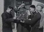 Seminarians and a Chinese priest marveling at a bird in a bird cage by Fr. Charles Meeus