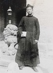 Fr. Paul Yu Bin standing next to a Chinese stone lion